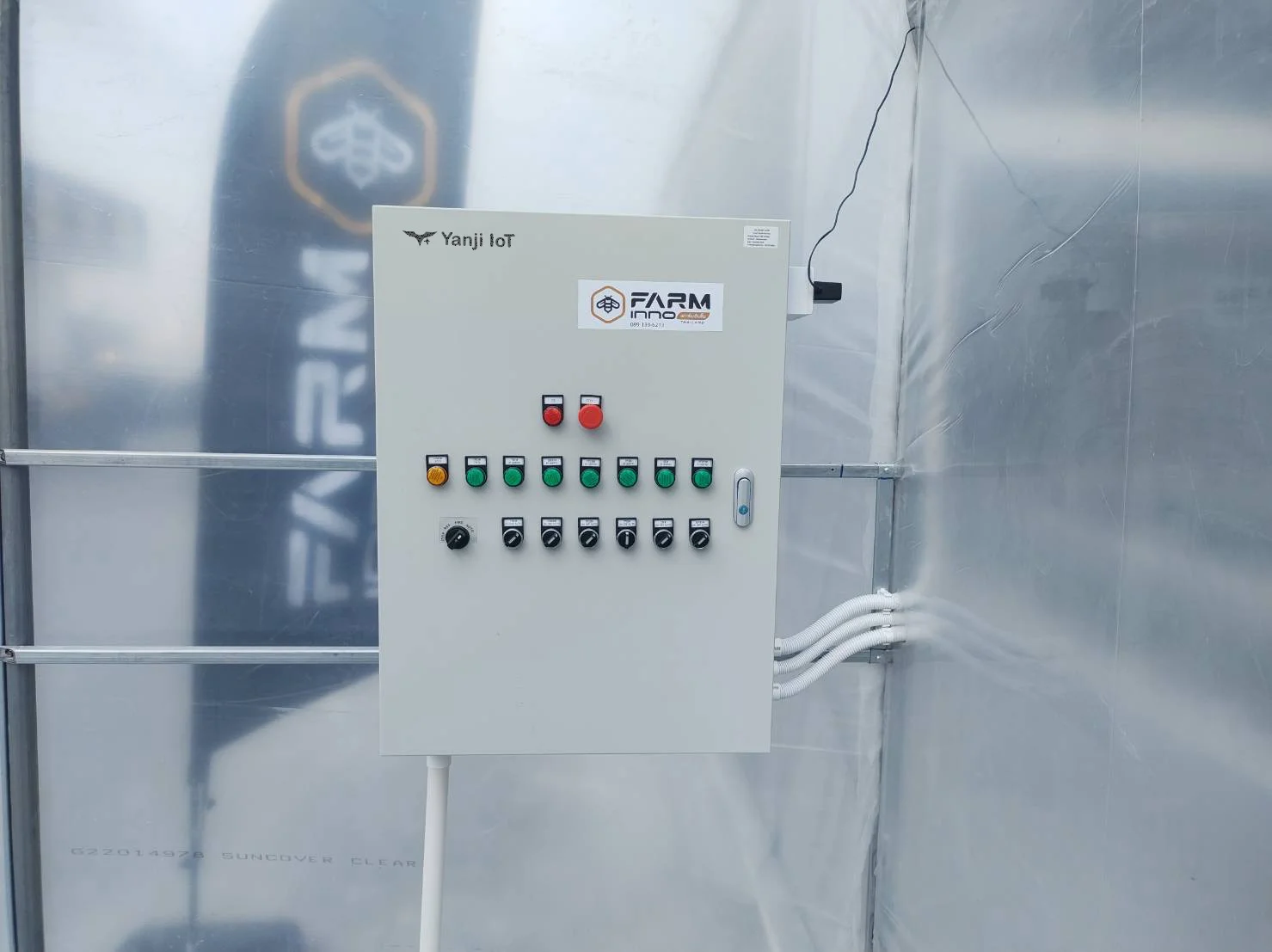 Greenhouse control cabinet with run lights and selector switches inside a film greenhouse